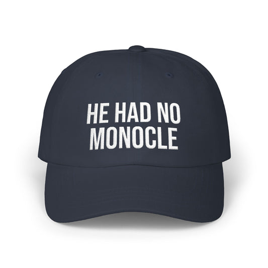 Navy blue cap with white text 'HE HAD NO MONOCLE' on a white background
