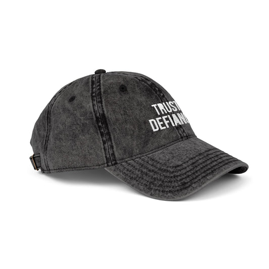 Black denim cap with 'TRUST DEFIANC' text on a white background side view