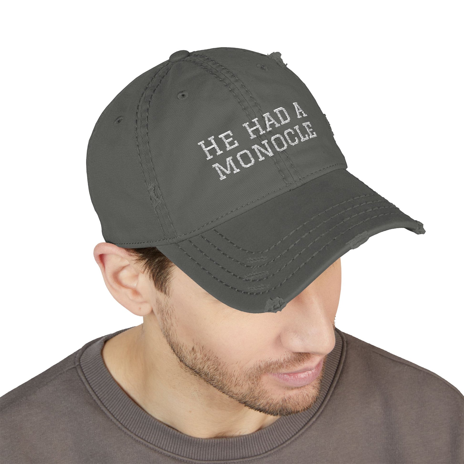 Man wearing a dark gray cap with 'HE HAD A MONOCLE' text on a white background