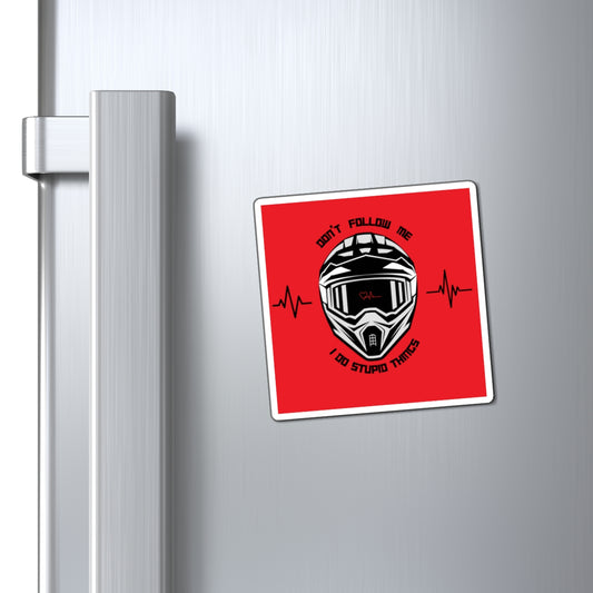 Fridge magnet with a helmet design and text on a red background attached to a refrigerator.