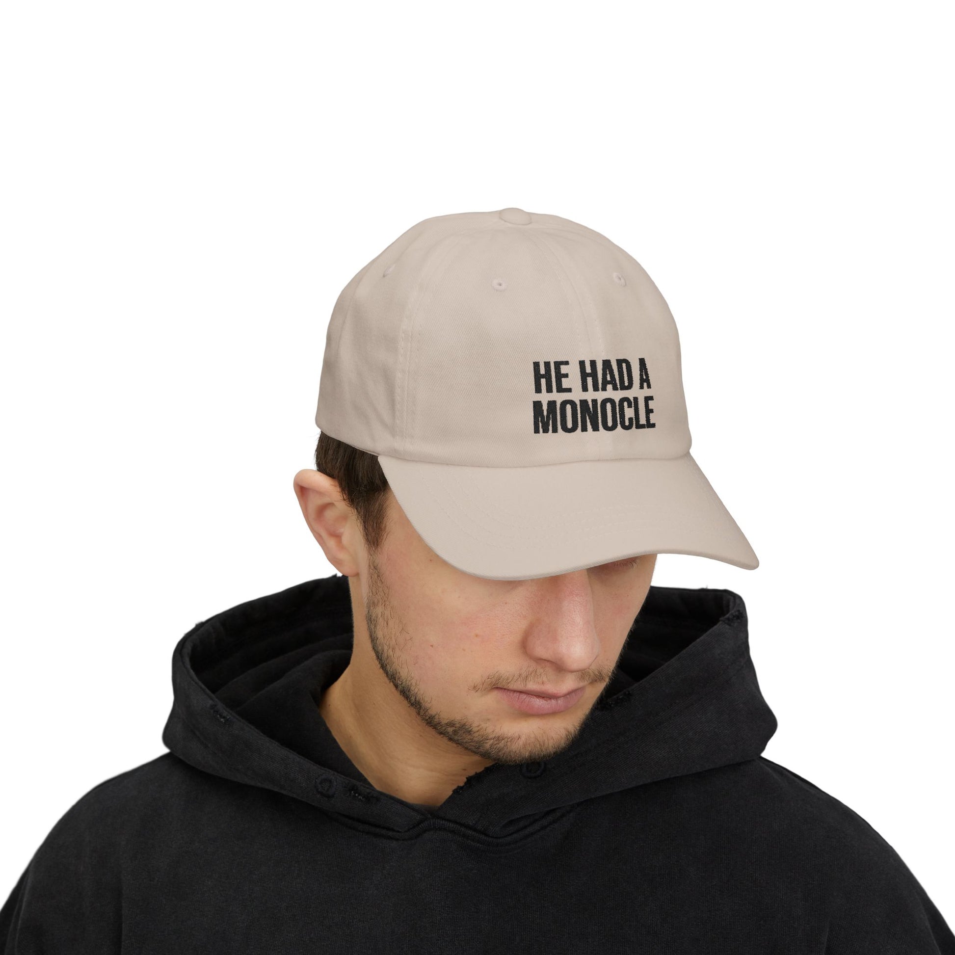 Man wearing a beige cap with 'HE HAD A MONOCLE' text on a white background