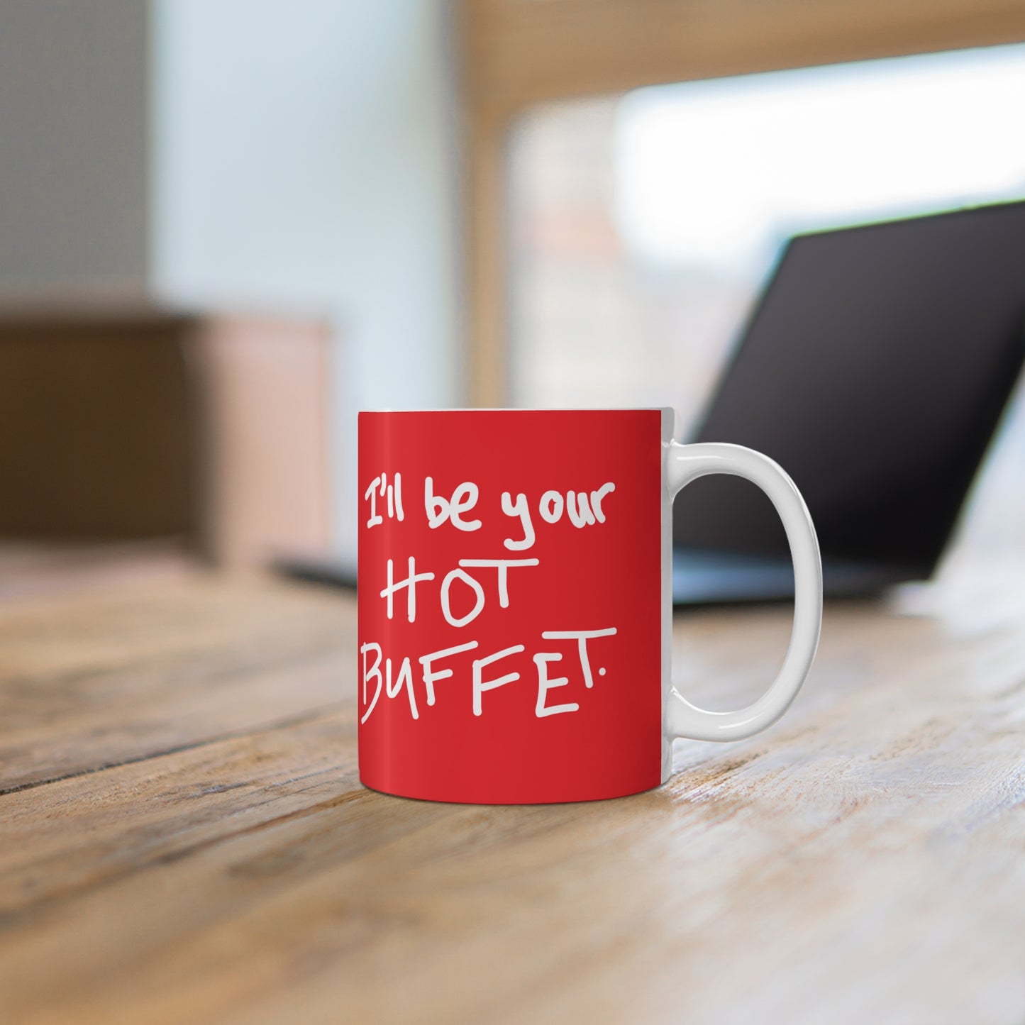 Red mug with 'I'll be your hot buffet' text on a wooden surface.