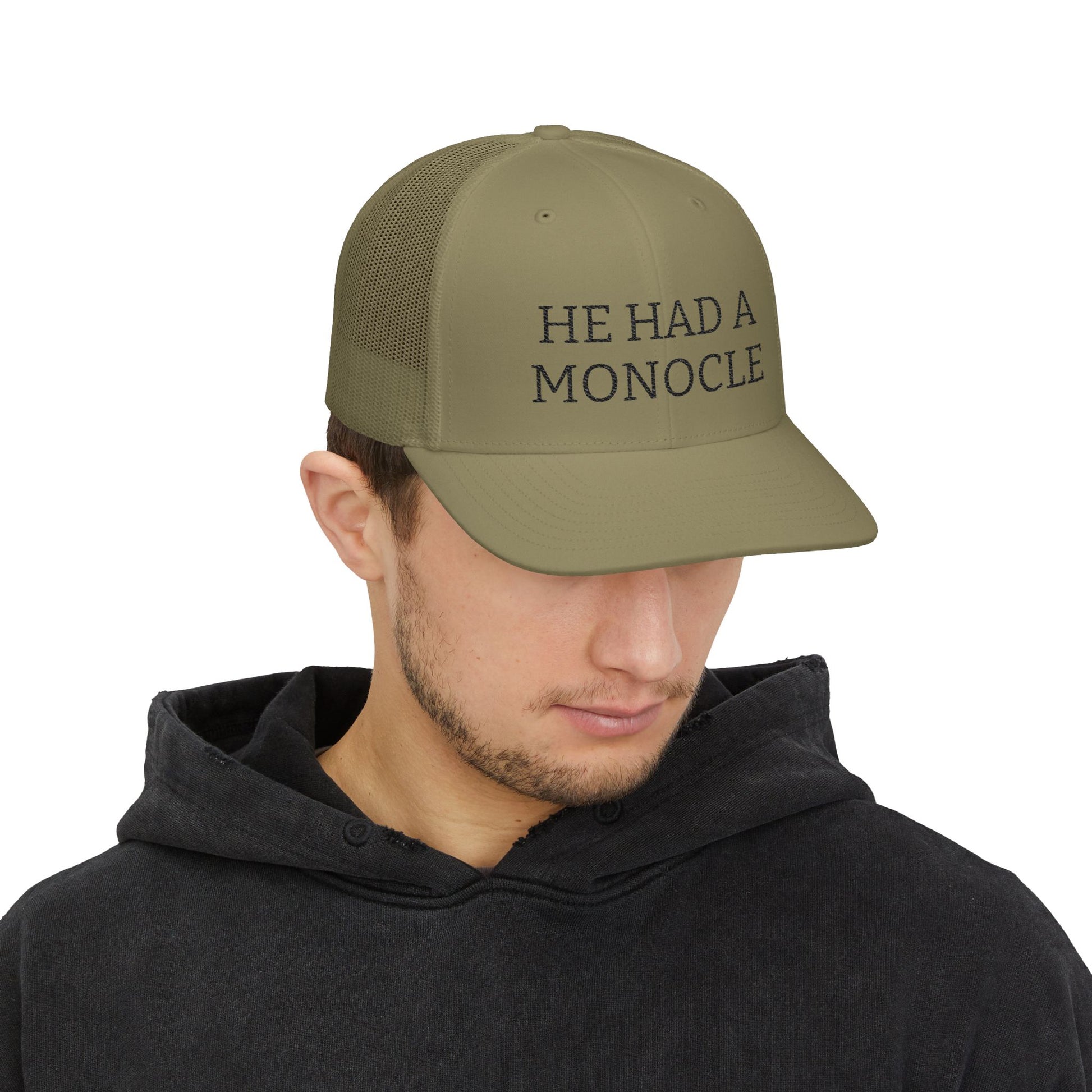Man wearing a green cap with text 'HE HAD A MONOCLE' on a white background