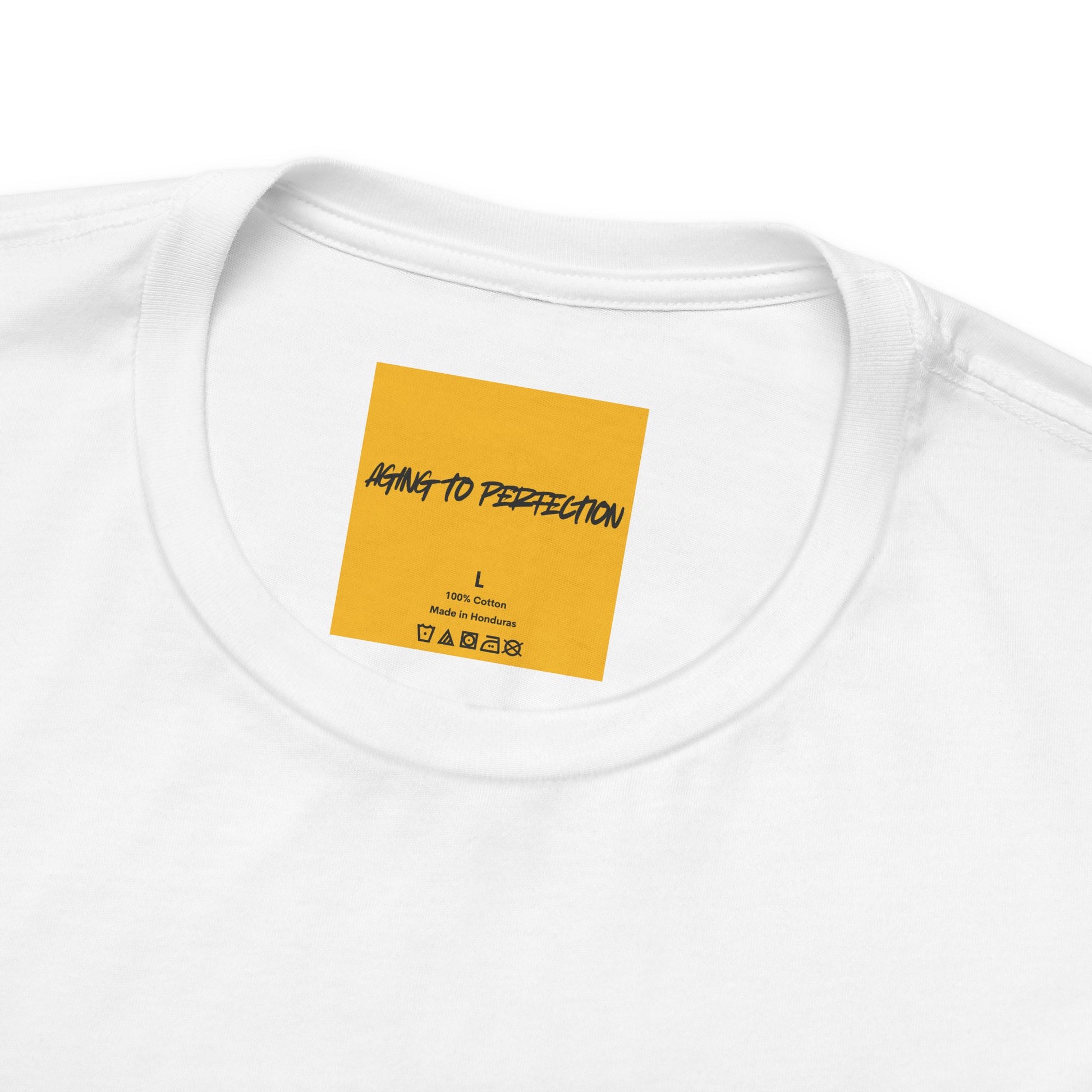 close up of yellow neck label AGING TO PERFETION on white tee
