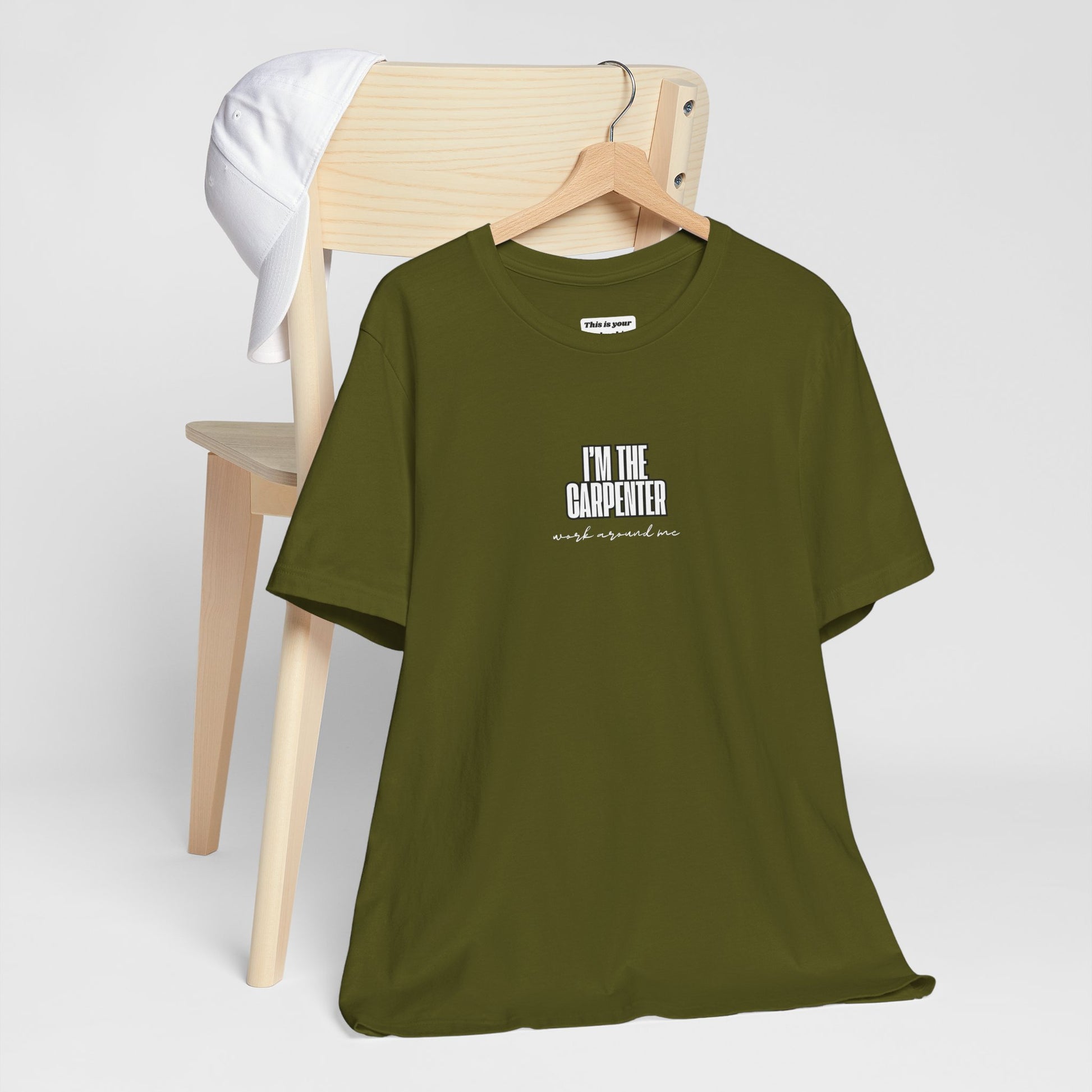 olive green unisex t-shirt with I'M THE CARPENTER WORK AROUND ME text  on a hanger from cahir