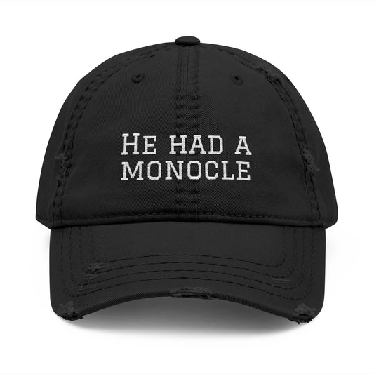 Black cap with 'He Had a Monocle' text on a white background