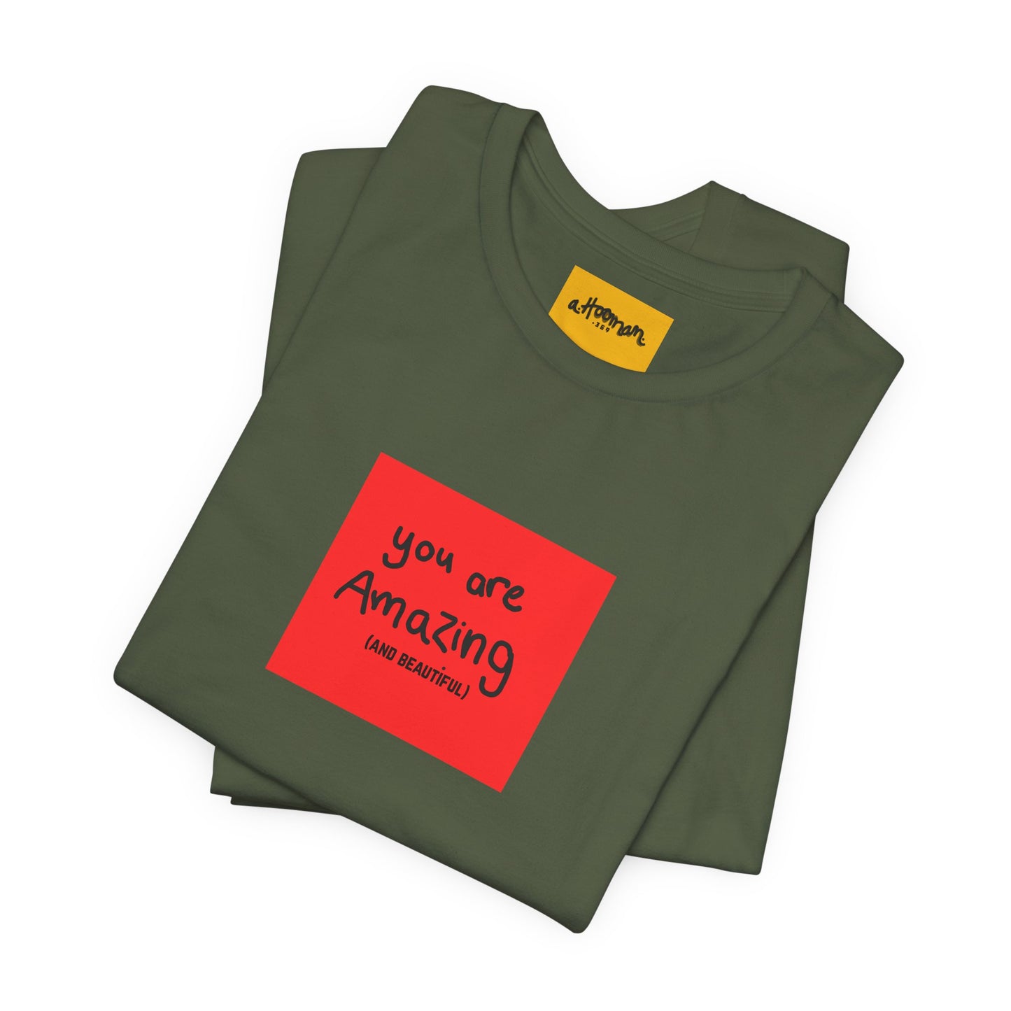 Folded green t-shirt with a red square and text reads You are Amazing and beautiful  on a white background