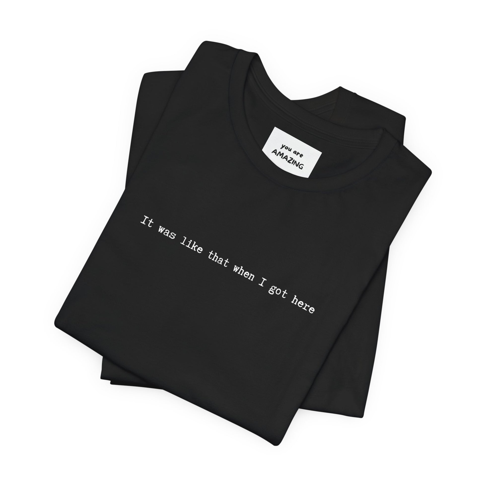close up folded unisex t-shirt with white IT WAS LIKE THAT WHEN I GOT HERE text - funny sarcastic tee with hidden neck label message text YOU ARE AMAZING